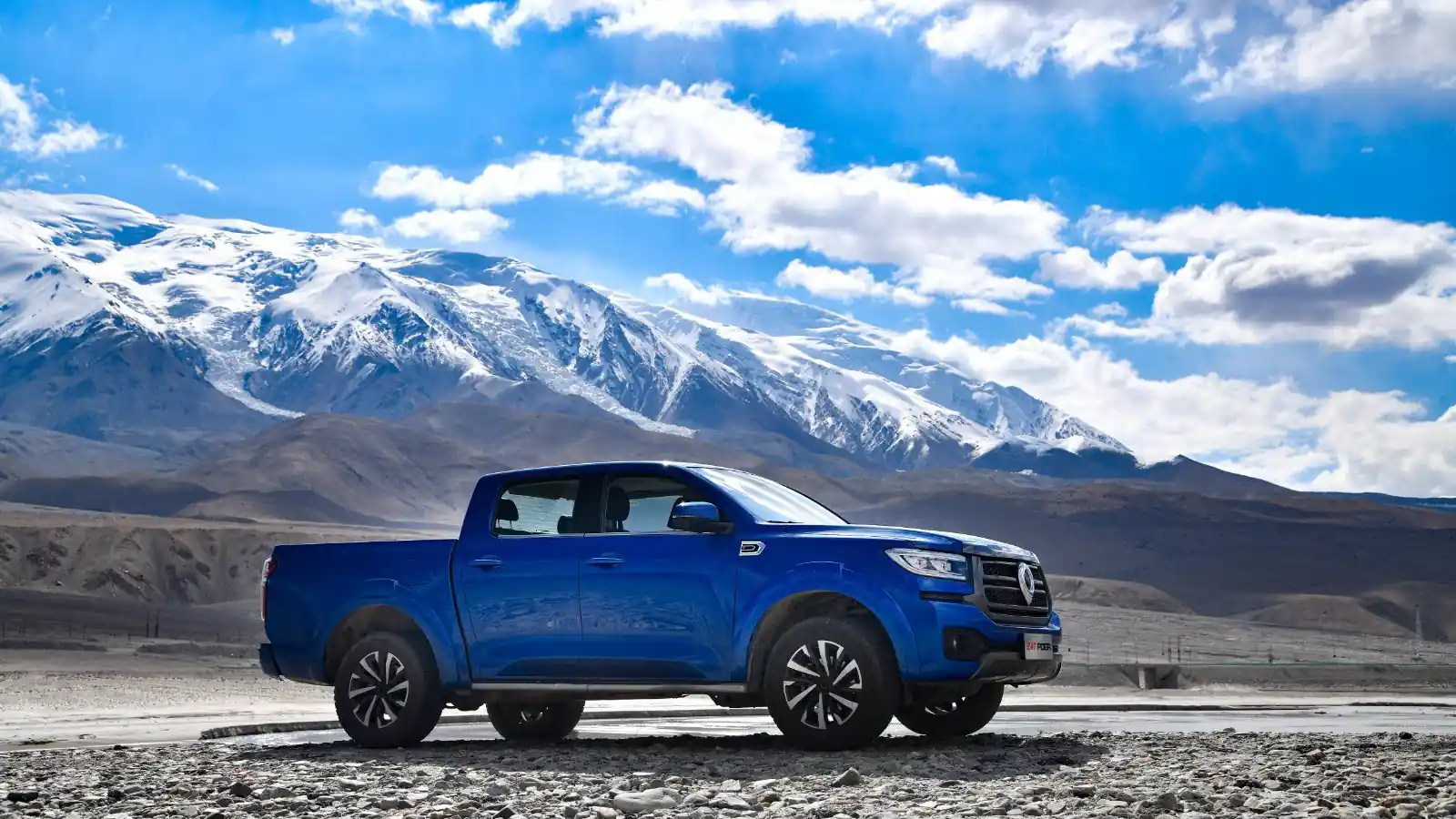 Синий пикап GWM POER 4WD на фоне заснеженных гор